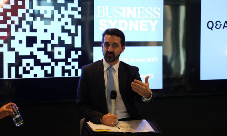 Paul Andon sitting with microphone and speaking at an event